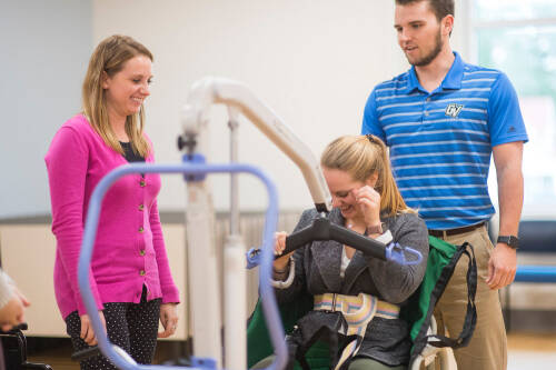 three students gather around a piece of therapeutic equipment
